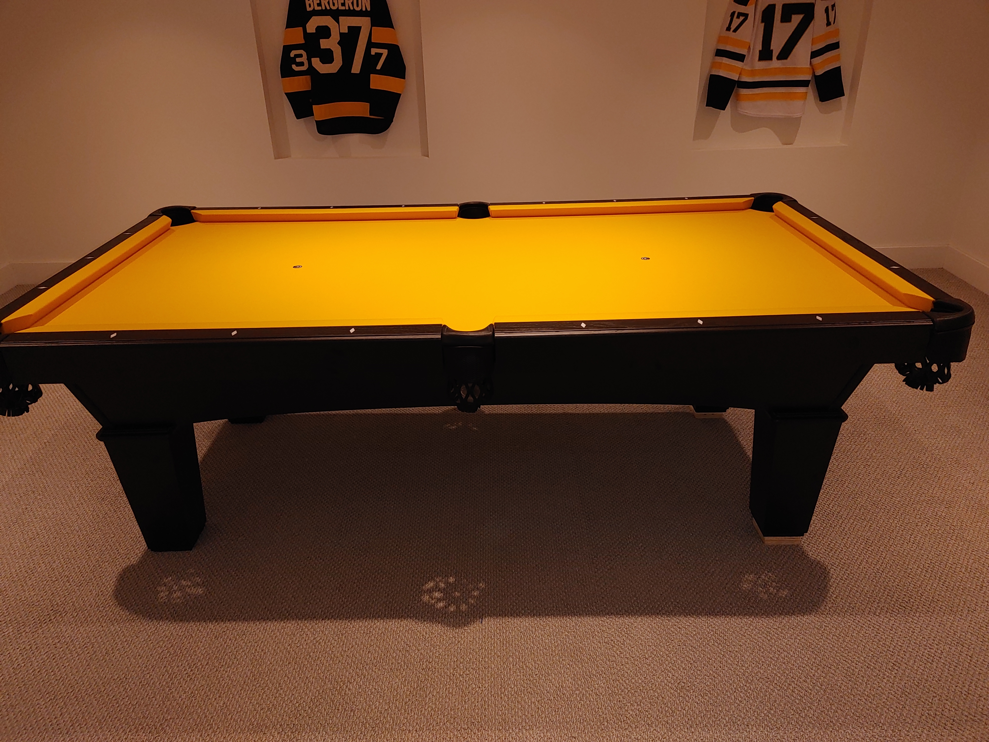 A yellow pool table under ceiling lights.