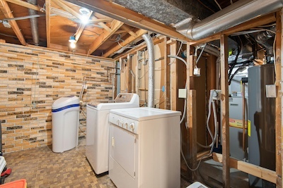 Basement laundry room with washer and dryer, water softener system, exposed ductwork and furnace.