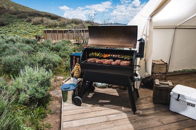 Large Traeger wood pellet grill on a wooden deck with desert mountains in the background.