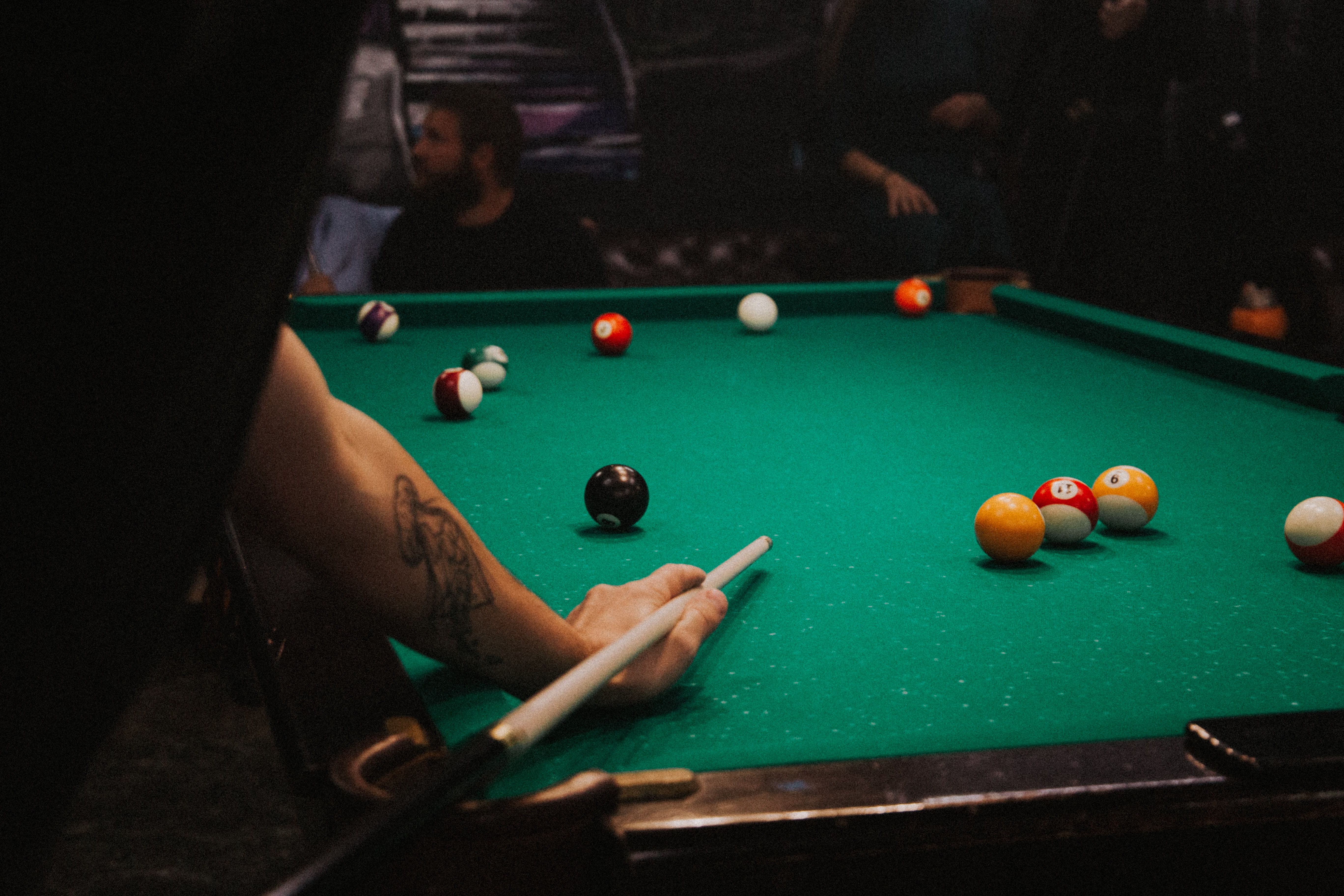 A man going to strike the cue ball on a pool table with a green cloth.