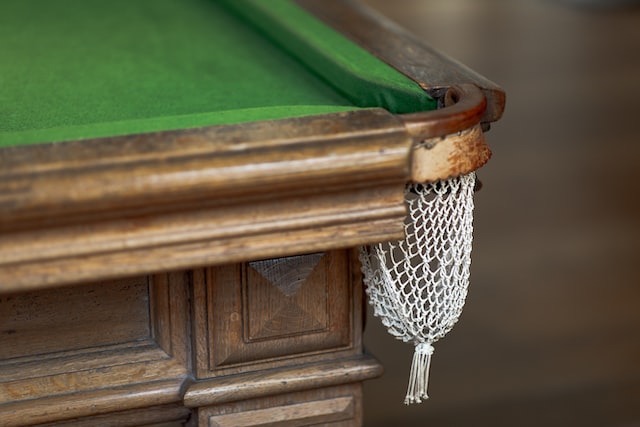 Corner of a snooker table with green felt and a white fabric pocket net.