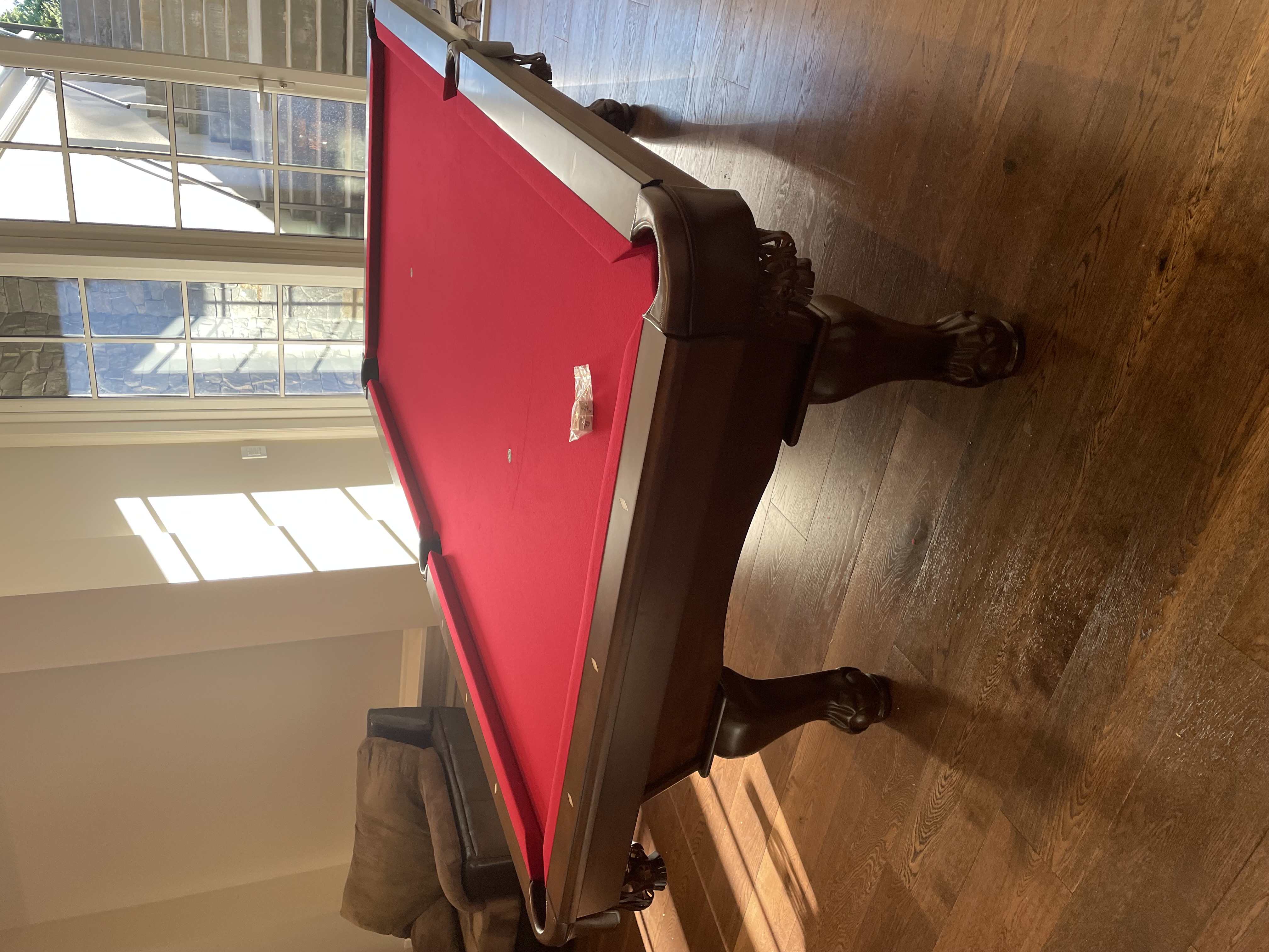 A red pool table in a sunlit room.