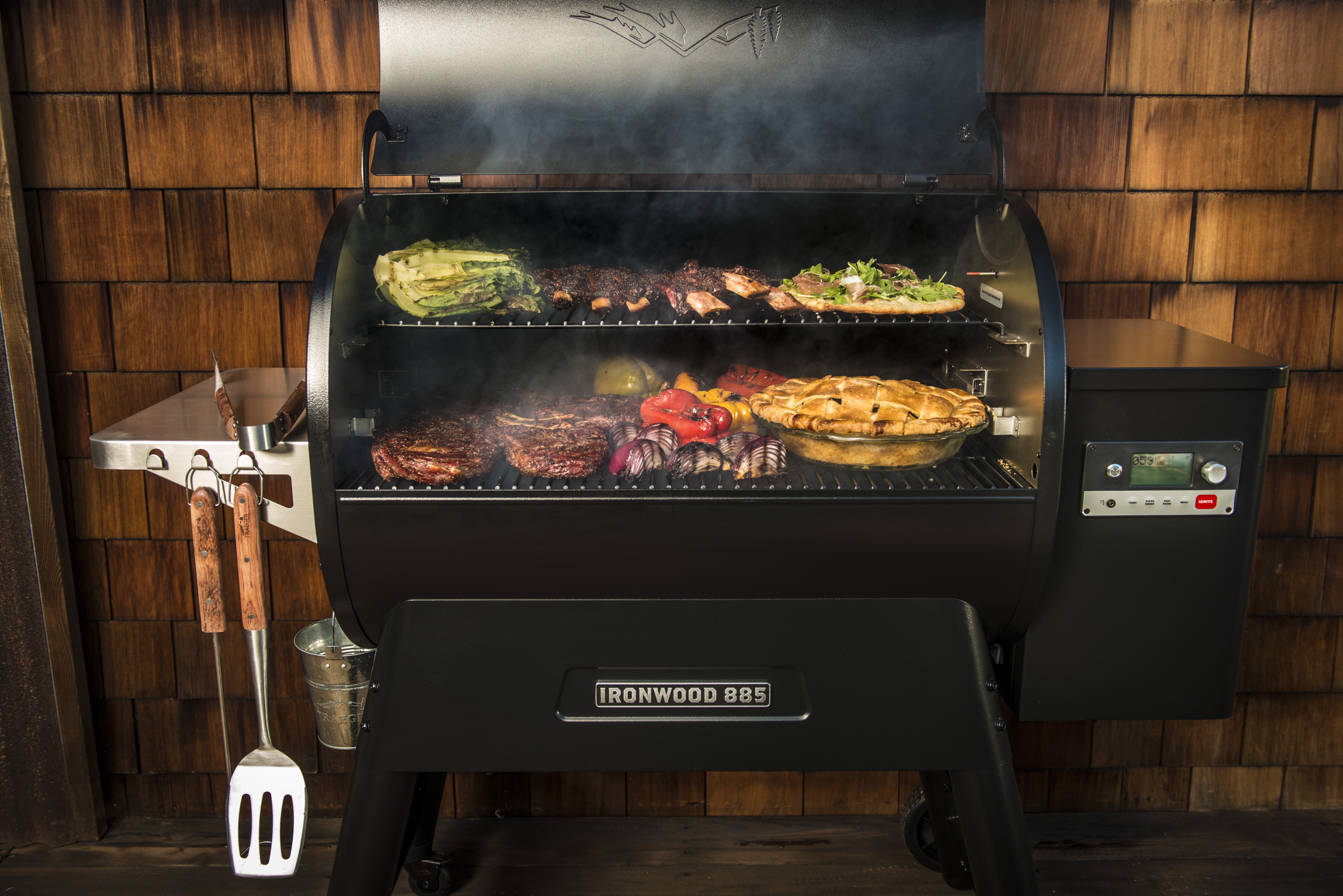 The Traeger Ironwood 885 with grill hood open and food on the grill.