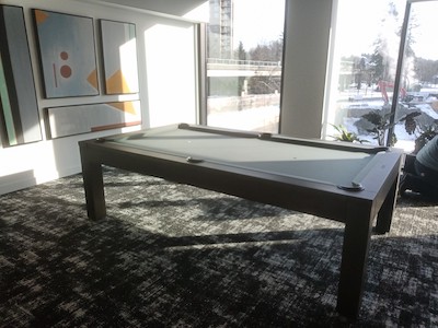  A modern pool table room with abstract art on wall and carpet flooring.