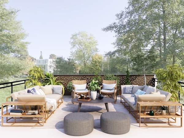 Patio seating area with outdoor couches and chairs and a coffee table. Large trees surround the space.