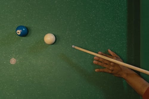 A pool cue aligned to a cue ball to hit a blue number 2 ball on a green felt pool table.