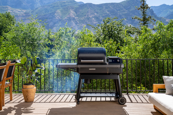 2023 Traeger Ironwood wood pellet grill on a patio deck with forest and mountains in the background.