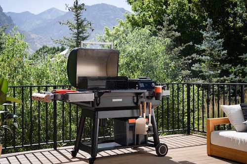 Traeger Ironwood wood pellet grill on a patio deck with mountains and trees in the background.