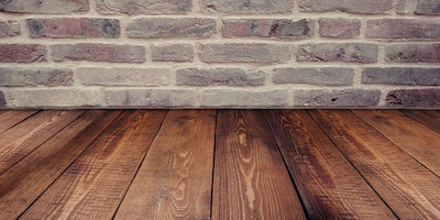 Medium brown wood floor with a brick wall.